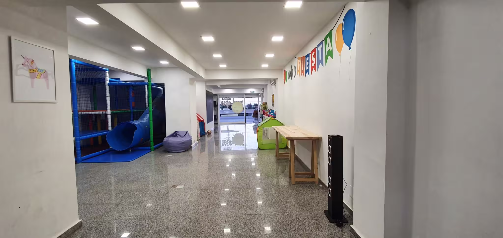 Sala de fiestas con mesas, zona infantil y decoración